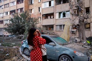 Women react as they stand at the site of a building which was hit by a Russian missile and drone strike amid Russia's attack on Ukraine in Kyiv
